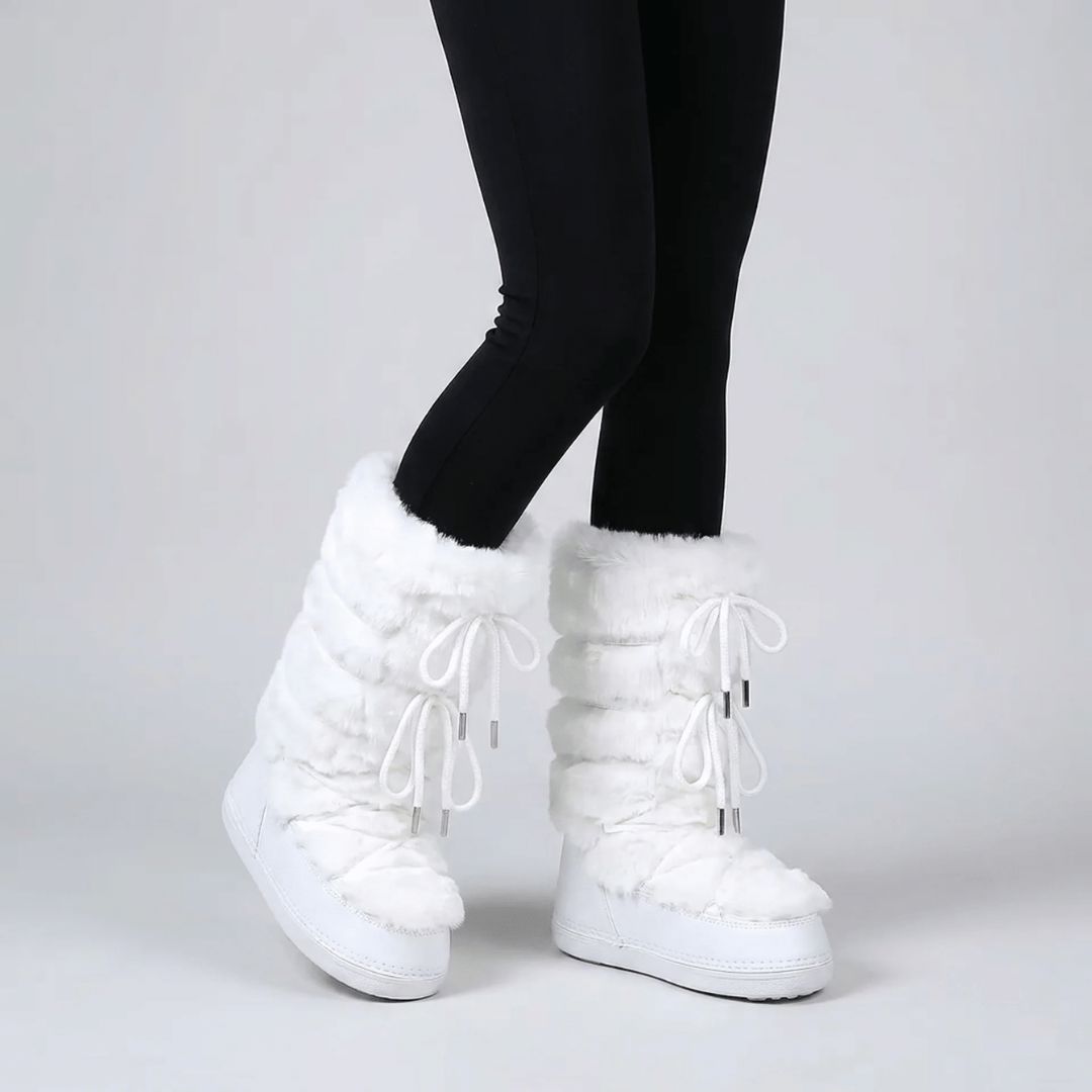Pair of women's fur lined snow boots set on the snow
